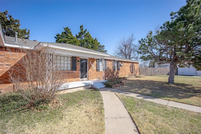 ranch-style home featuring brick siding, a front lawn, and fence