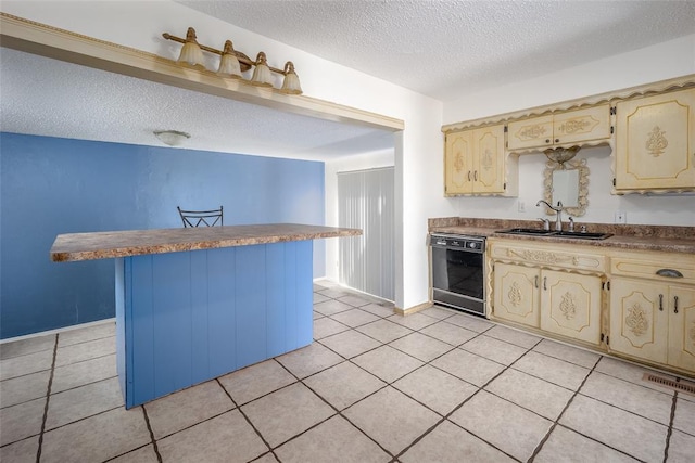 kitchen featuring visible vents, a sink, cream cabinets, light tile patterned flooring, and dishwasher