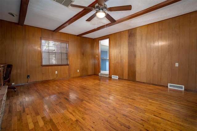 empty room featuring visible vents, beam ceiling, ceiling fan, and hardwood / wood-style flooring