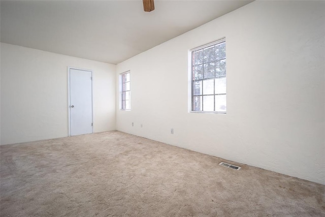 carpeted spare room with visible vents and a ceiling fan