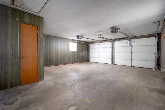 garage featuring wood walls and a garage door opener