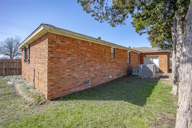 view of side of home with brick siding, fence, central air condition unit, a yard, and crawl space