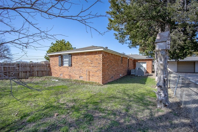 view of side of property featuring a lawn, fence, brick siding, and crawl space