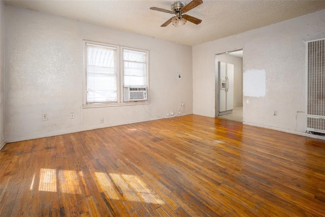 unfurnished room featuring a heating unit, ceiling fan, hardwood / wood-style floors, a textured wall, and a textured ceiling