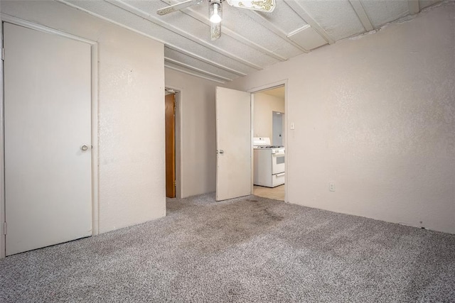 unfurnished bedroom featuring light colored carpet, ceiling fan, and a textured wall