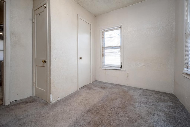 unfurnished bedroom featuring carpet flooring, a textured ceiling, and a textured wall