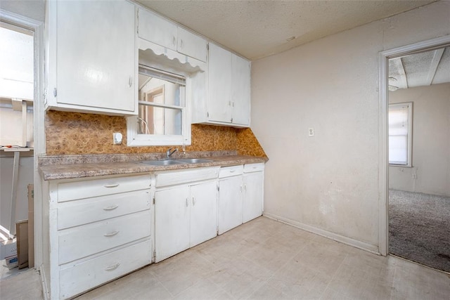 kitchen with light countertops, white cabinets, light floors, and a sink