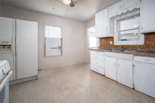 kitchen featuring a sink, white appliances, light floors, and white cabinetry