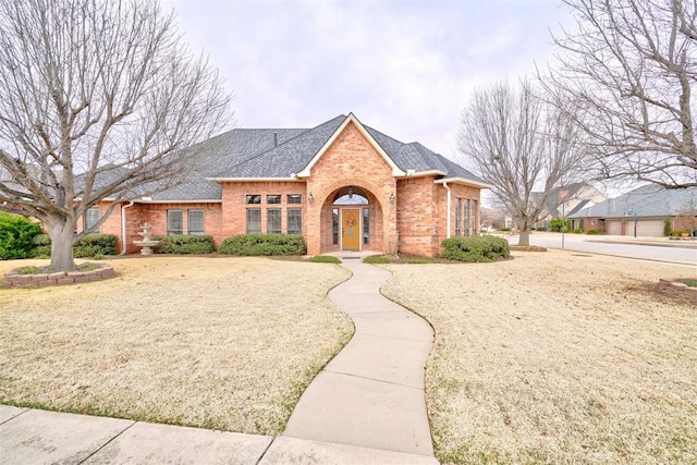 view of front of home featuring brick siding and roof with shingles