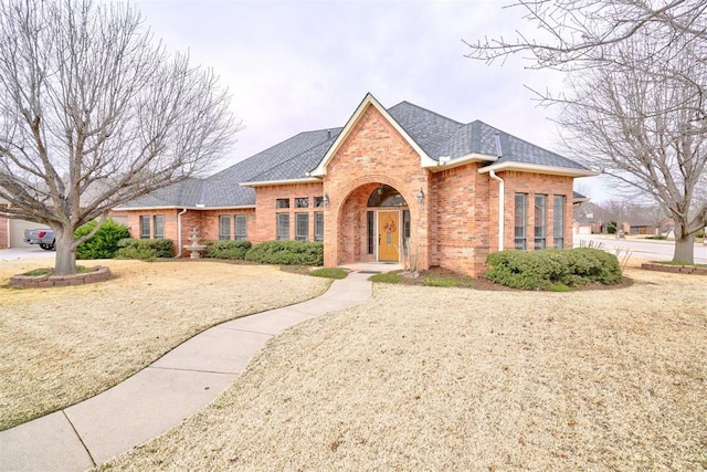 view of front of home featuring brick siding and roof with shingles