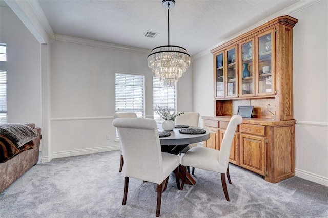 dining space with visible vents, baseboards, light colored carpet, ornamental molding, and a notable chandelier