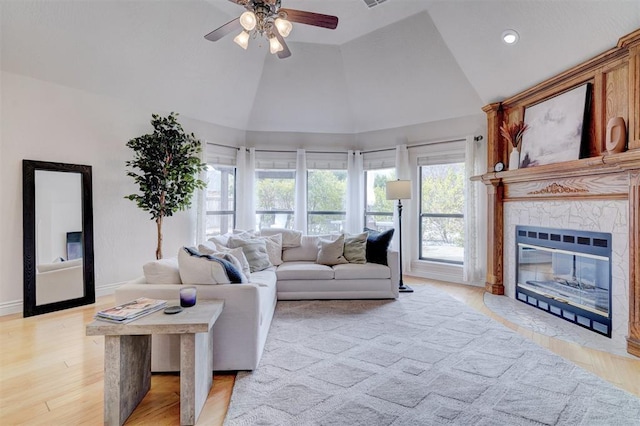 living room with baseboards, a premium fireplace, recessed lighting, light wood-style flooring, and high vaulted ceiling