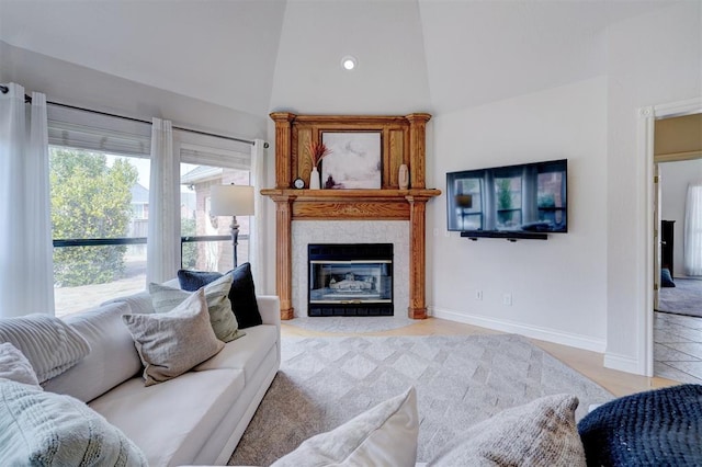 living room with high vaulted ceiling, baseboards, and a tile fireplace