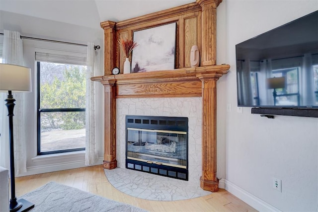 room details featuring a fireplace with flush hearth, wood finished floors, and baseboards