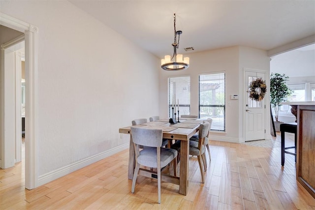 dining room featuring light wood-type flooring, baseboards, an inviting chandelier, and visible vents