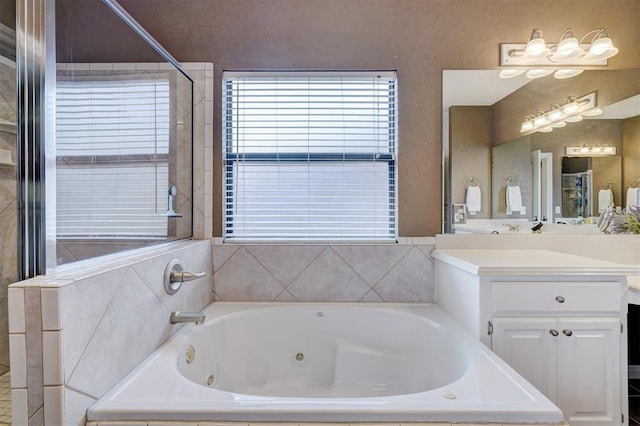 bathroom with a healthy amount of sunlight, a jetted tub, and vanity