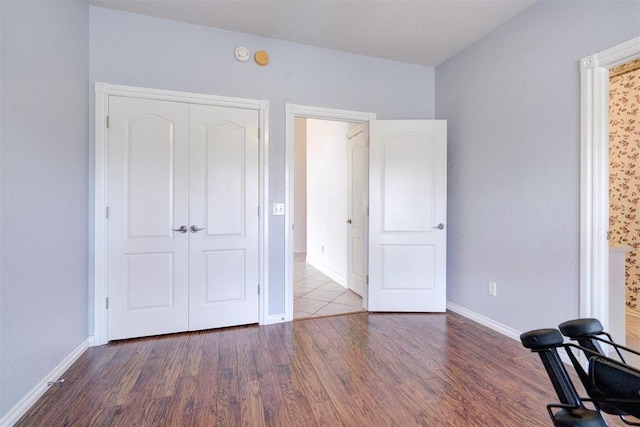 unfurnished bedroom featuring wood finished floors, baseboards, and a closet