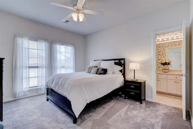 bedroom featuring visible vents, light colored carpet, ensuite bath, and multiple windows