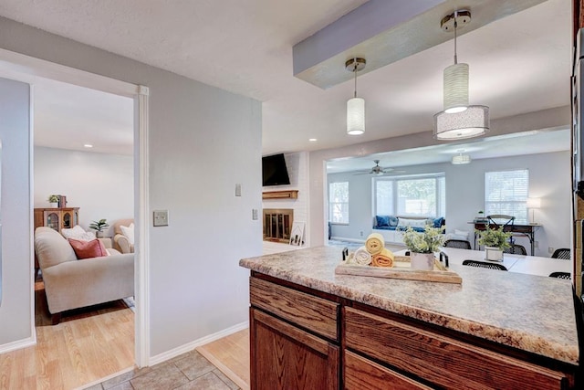 kitchen with decorative light fixtures, open floor plan, a brick fireplace, and light countertops