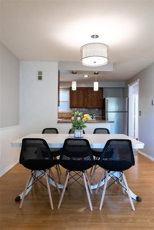 dining space featuring light wood-style floors, visible vents, and baseboards