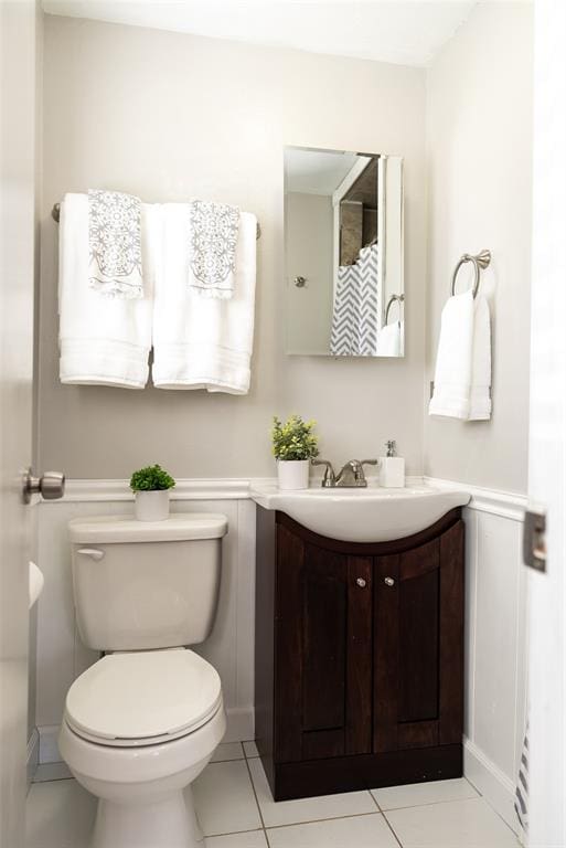 bathroom with a decorative wall, wainscoting, toilet, and vanity