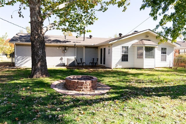 back of house with a yard, fence, brick siding, and an outdoor fire pit