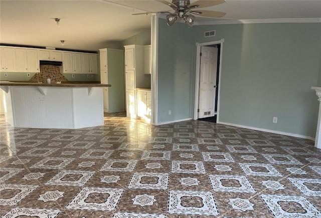 kitchen featuring dark countertops, baseboards, visible vents, and ornamental molding