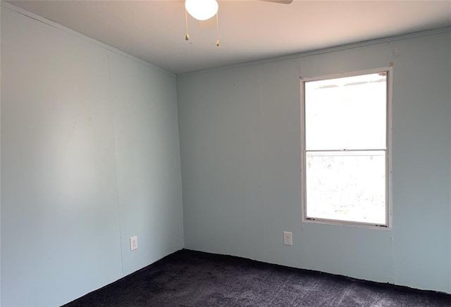 empty room featuring dark colored carpet and a ceiling fan