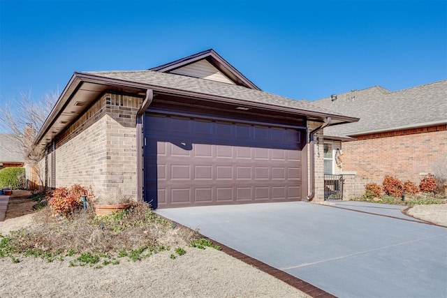 view of front facade featuring brick siding, an attached garage, concrete driveway, and roof with shingles