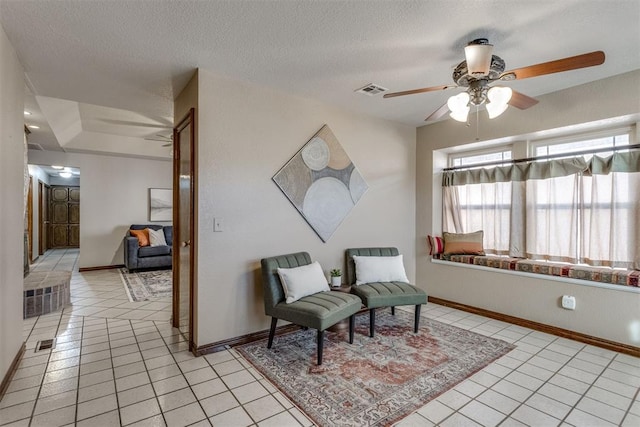 living area with light tile patterned floors, visible vents, a textured ceiling, and a ceiling fan