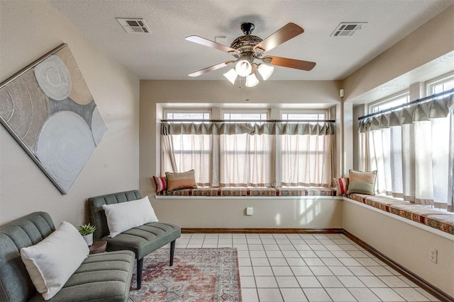 living area with light tile patterned floors, visible vents, a textured ceiling, and baseboards