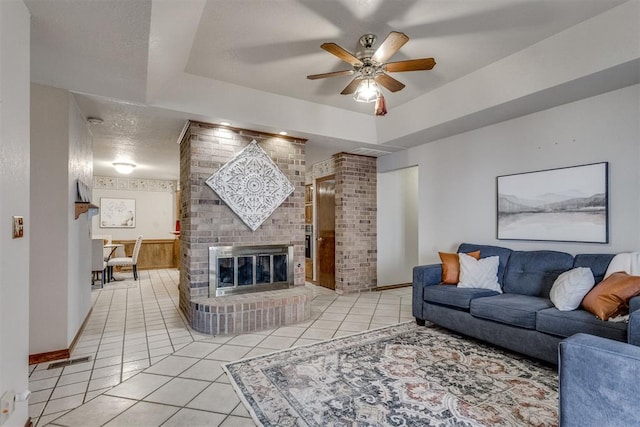 living room with tile patterned floors, visible vents, a textured ceiling, and a raised ceiling