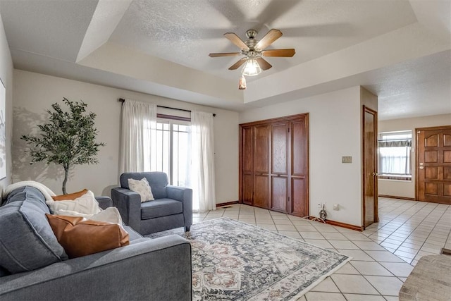 living room with light tile patterned floors, a healthy amount of sunlight, a textured ceiling, and a raised ceiling