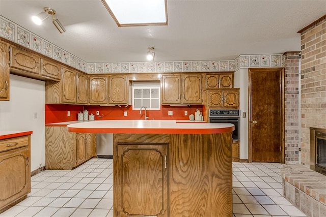 kitchen with light tile patterned flooring, black oven, a brick fireplace, and light countertops