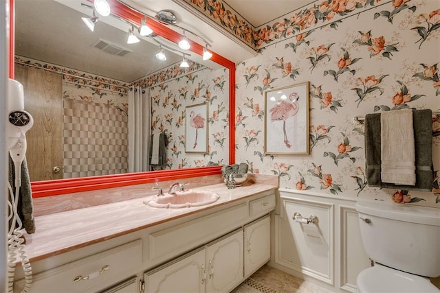 bathroom featuring vanity, visible vents, wallpapered walls, wainscoting, and toilet