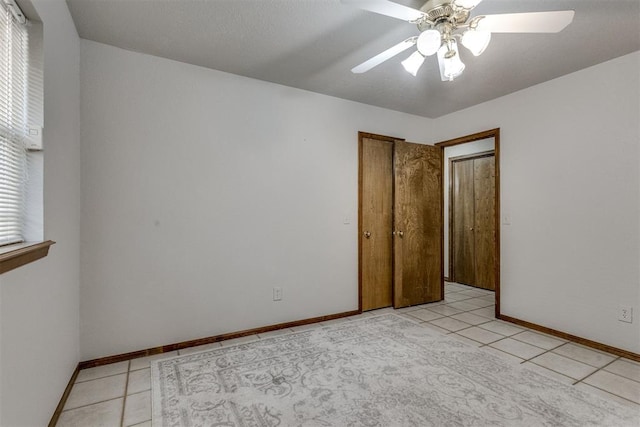 empty room featuring light tile patterned floors, baseboards, and a ceiling fan