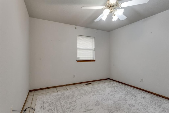 empty room with light tile patterned flooring, baseboards, visible vents, and ceiling fan