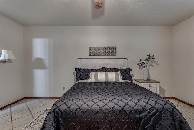 bedroom with light tile patterned flooring, a textured ceiling, a ceiling fan, and baseboards