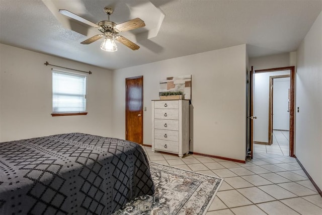 bedroom featuring light tile patterned floors, baseboards, a textured ceiling, and a ceiling fan