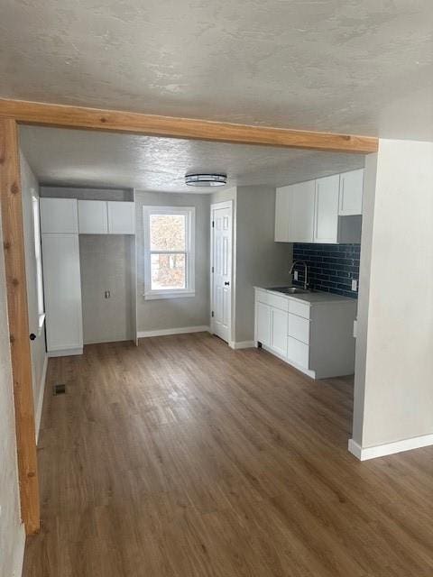 kitchen with decorative backsplash, white cabinets, and wood finished floors