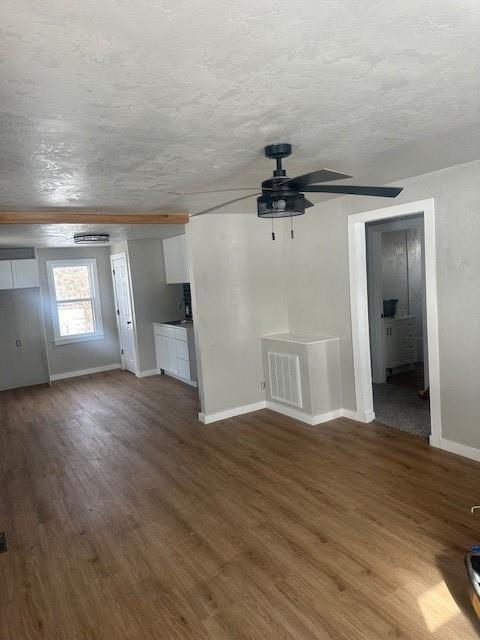 unfurnished living room featuring visible vents, a textured ceiling, wood finished floors, baseboards, and ceiling fan