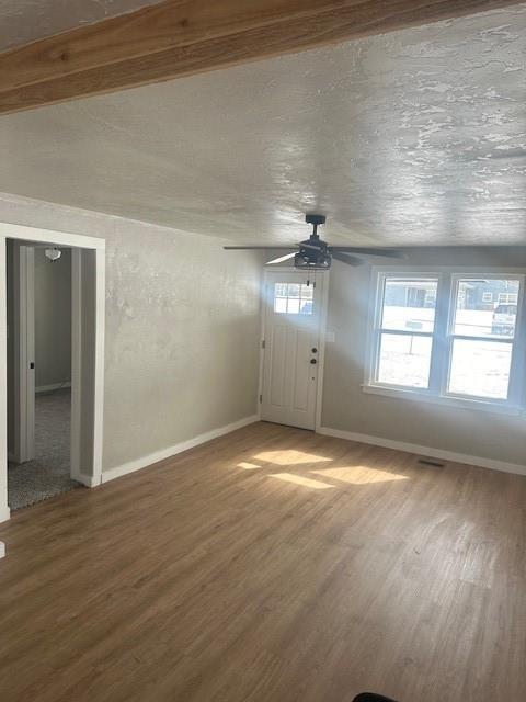 unfurnished living room featuring wood finished floors, baseboards, and ceiling fan