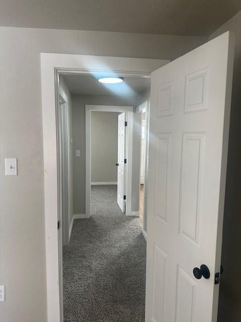 corridor featuring baseboards and carpet flooring