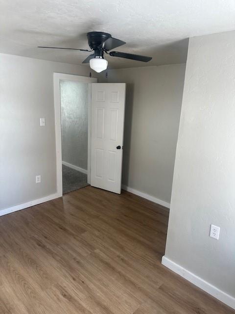 empty room with wood finished floors, baseboards, and ceiling fan