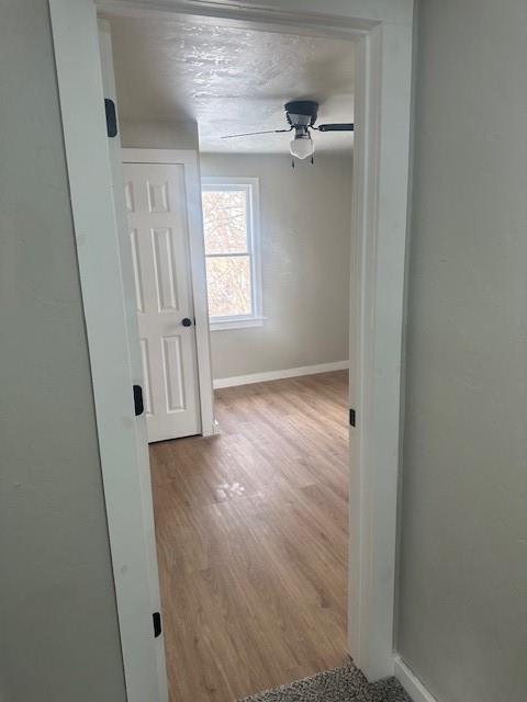 hallway featuring wood finished floors and baseboards