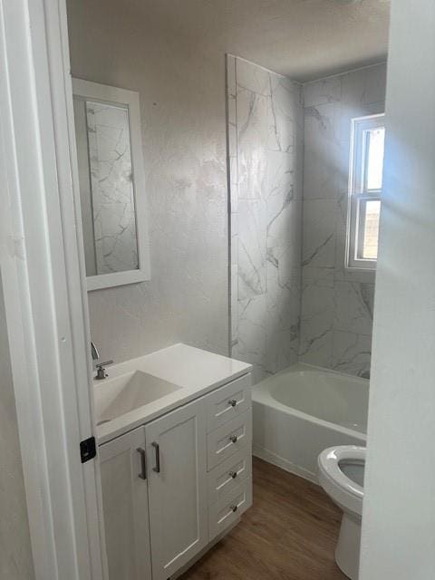 bathroom with toilet, shower / washtub combination, wood finished floors, and vanity