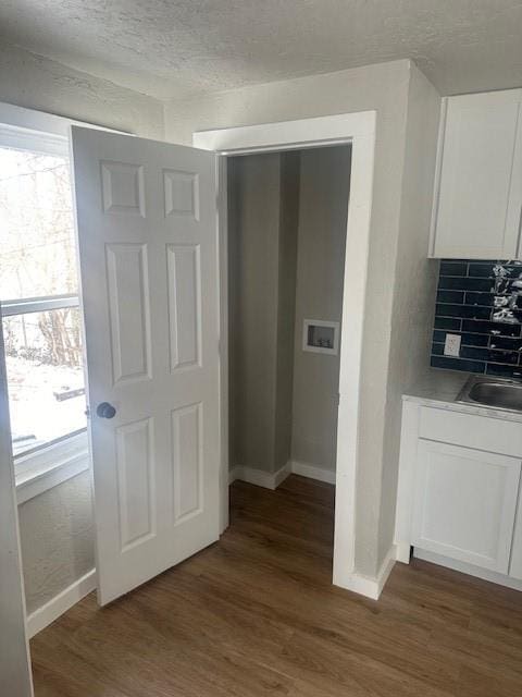 hallway with dark wood-type flooring, plenty of natural light, baseboards, and a sink