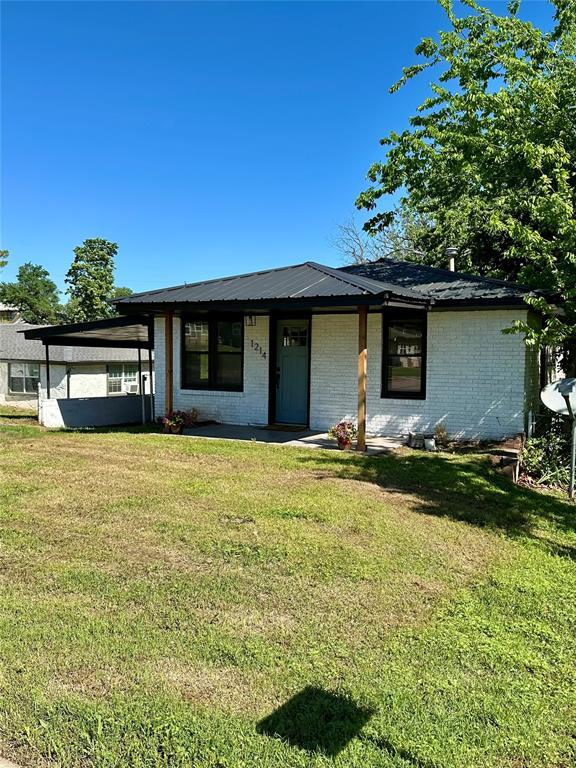 1214 E Cleveland Ave, Guthrie, OK 73044 - view of front of home featuring brick siding, an attached carport, and a front yard