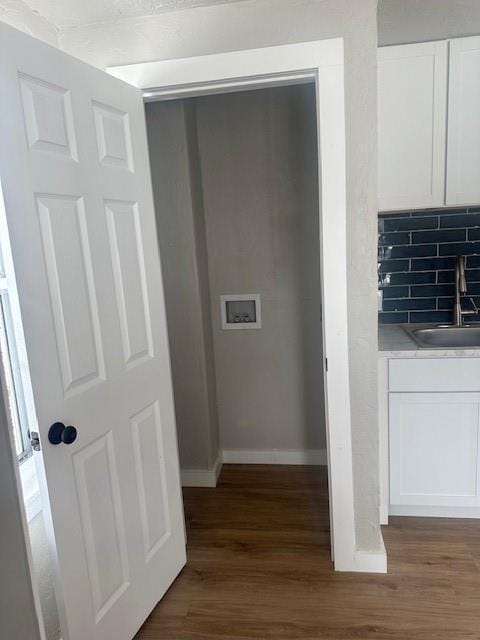 1214 E Cleveland Ave, Guthrie, OK 73044 - room details featuring a sink, baseboards, backsplash, and wood finished floors