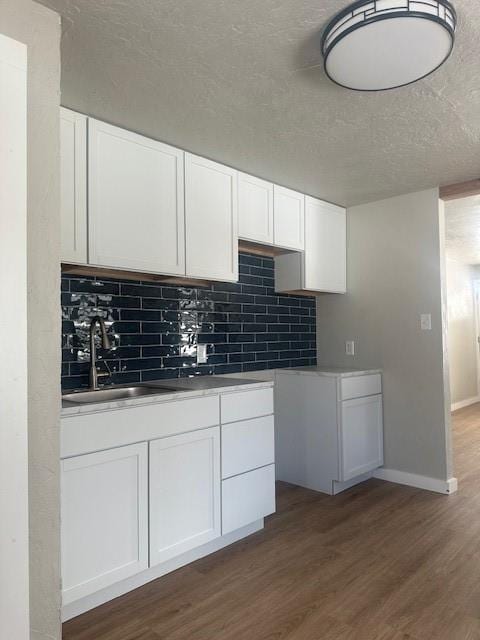 1214 E Cleveland Ave, Guthrie, OK 73044 - kitchen with dark wood-style flooring, a textured ceiling, decorative backsplash, and a sink